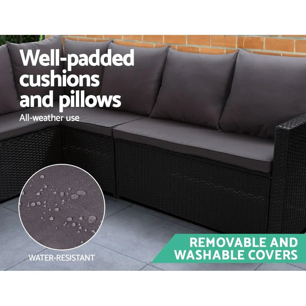 Outdoor furniture set with black wicker sofa pieces and beige cushions on stone patio
