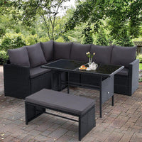 Black wicker corner sofa unit with cushions, part of modular outdoor dining furniture set