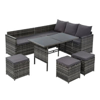 Outdoor 9-seater wicker sofa set arranged in a garden setting with light cushions.