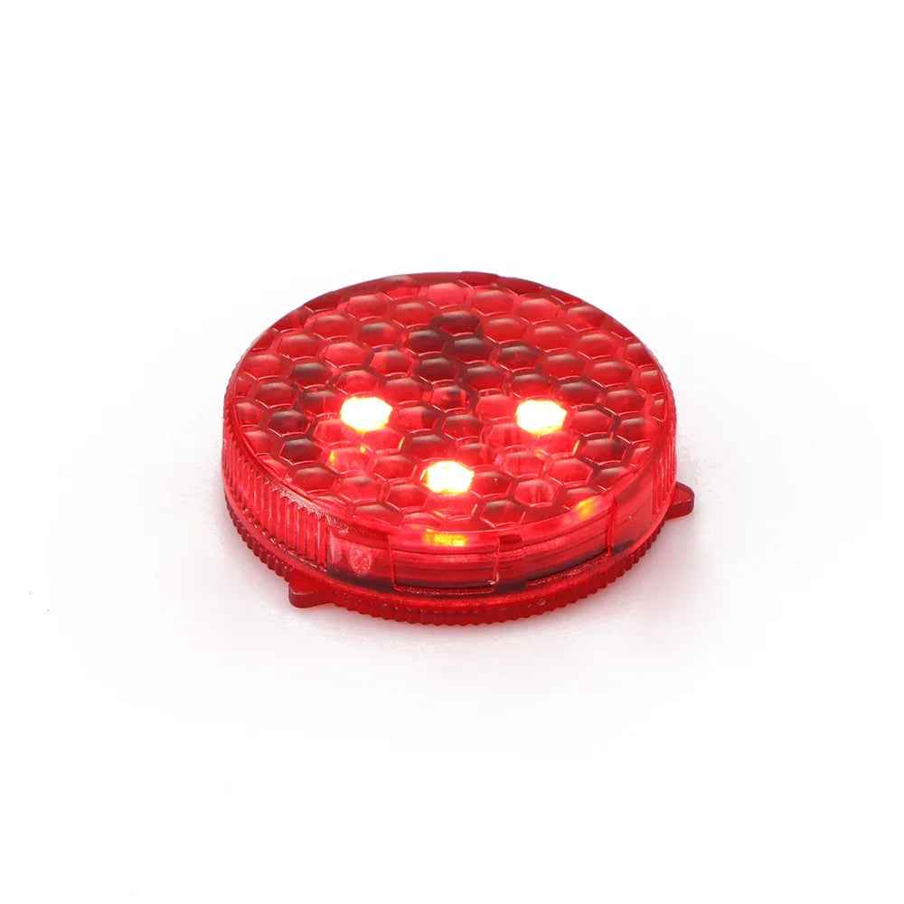 A pair of small round wireless car door warning lights glowing red on an open vehicle door at night.