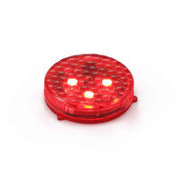 A pair of small round wireless car door warning lights glowing red on an open vehicle door at night.