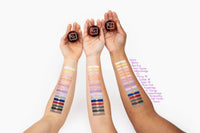 Hand swatching rich purple Sugar Hill Shimmer Powder on skin showing vibrant, creamy shimmer.