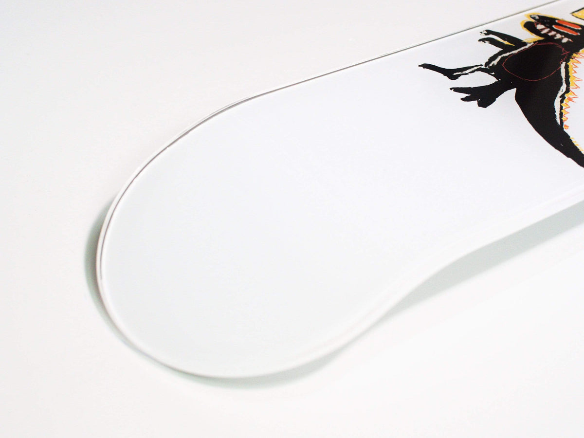 Skateboard resting against wall, showcasing dino design and grip tape on top