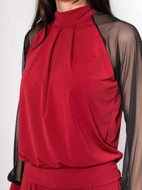 Close-up of garnet palazzo pants featuring front pleats and elastic waistband on model.