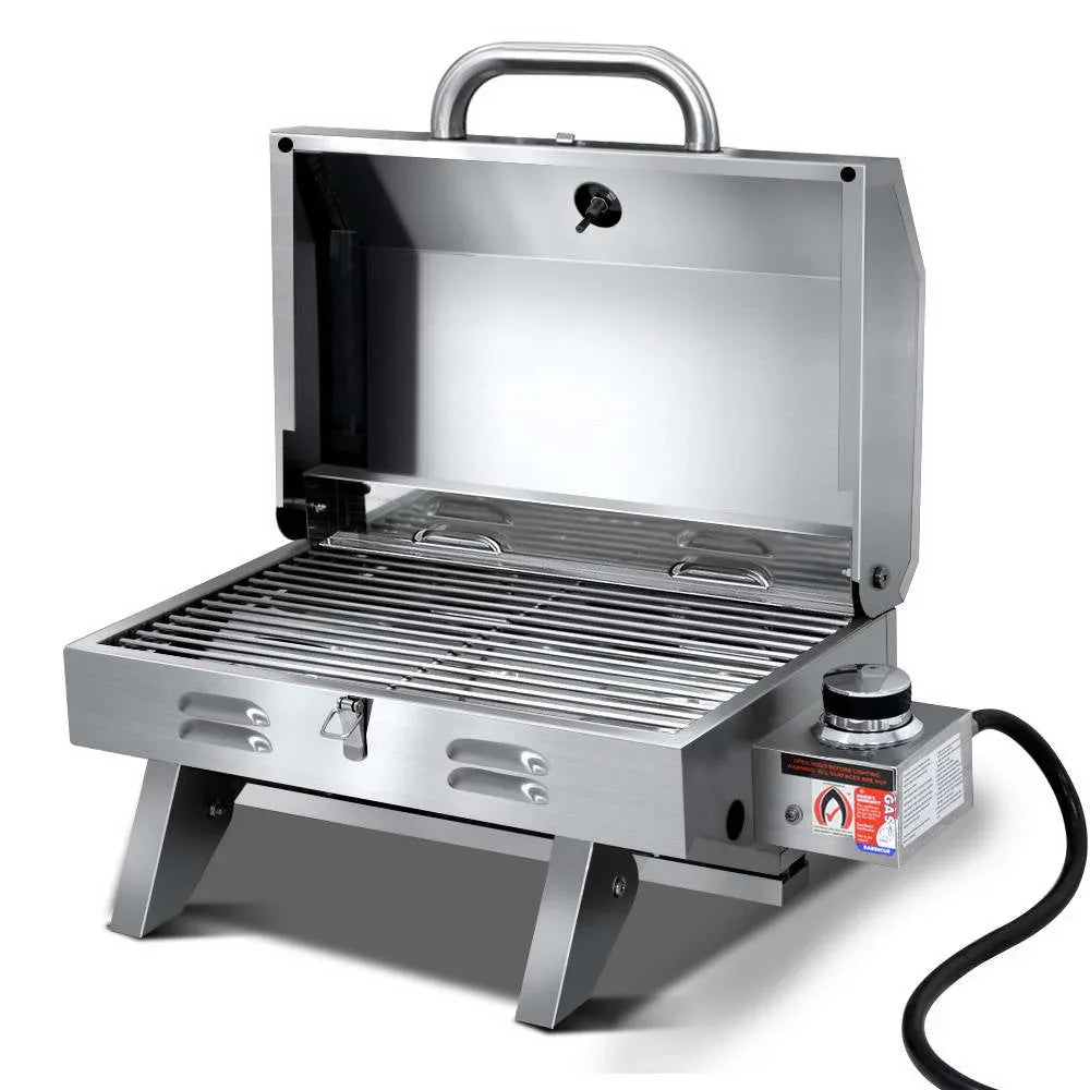 Compact stainless steel portable gas BBQ grill with closed locking lid and front carry handle.