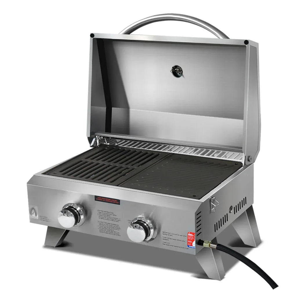 Top view of two-burner portable gas BBQ stove with stainless steel finish and locking lid closed.