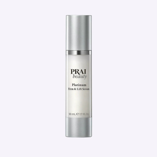 Bottle of PRAI Beauty Platinum Firm & Lift Serum 50ml with silver and white packaging on white background.