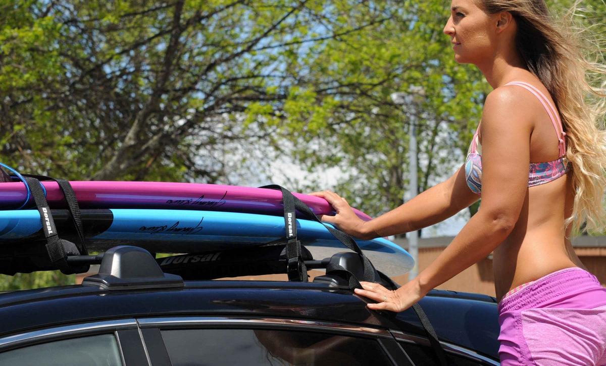 Black DORSAL Aero roof rack pads installed on car roof with snowboards mounted.