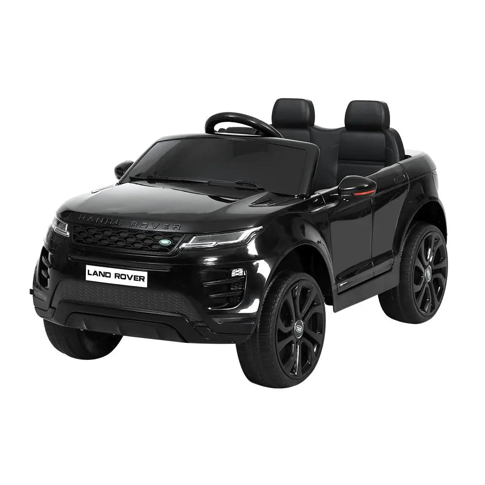 Black kids ride on Land Rover Evoque electric car with headlights on, viewed from front left.
