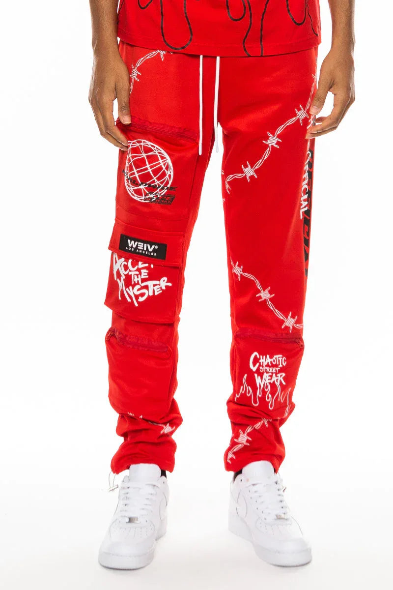 Red men's track pants with digital print and zippered pouch pockets, front view