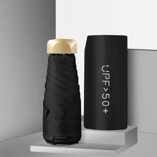 Mini umbrella unfolded next to matching black carrying pouch on white background.