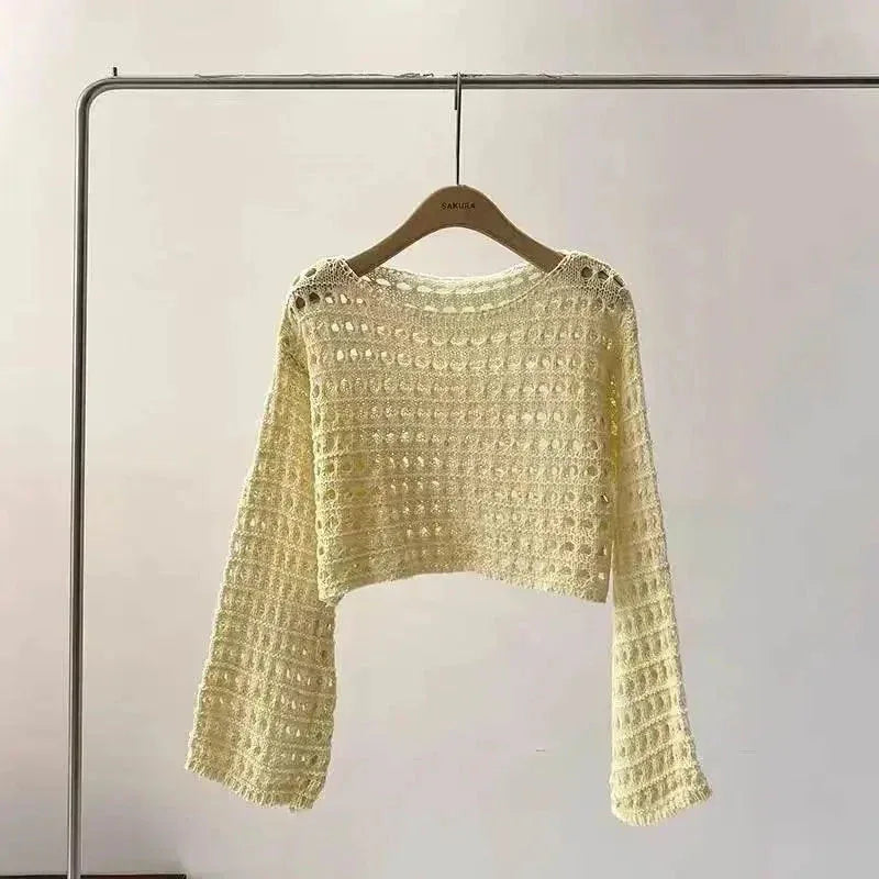 Flat lay of white crochet knit crop top with detailed knit pattern.