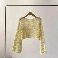 Flat lay of white crochet knit crop top with detailed knit pattern.