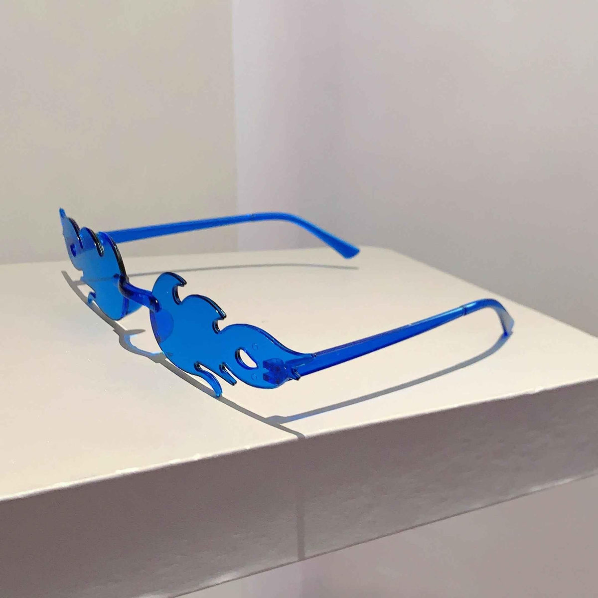 A set of 12 colorful flame-shaped sunglasses arranged stylishly on a white background.