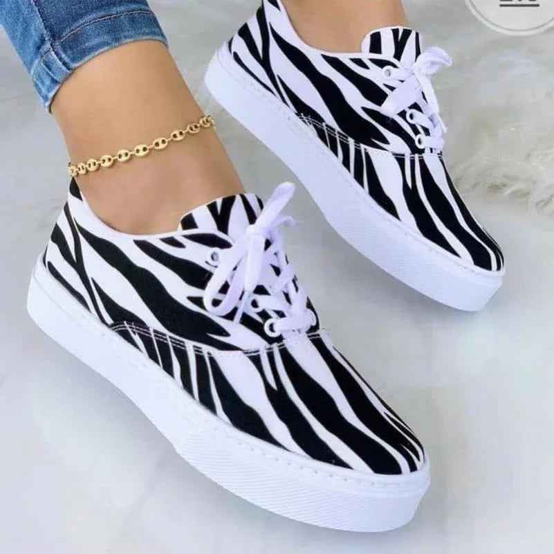 White women's sneakers with colorful graffiti designs and a chunky sole displayed on a clean background.