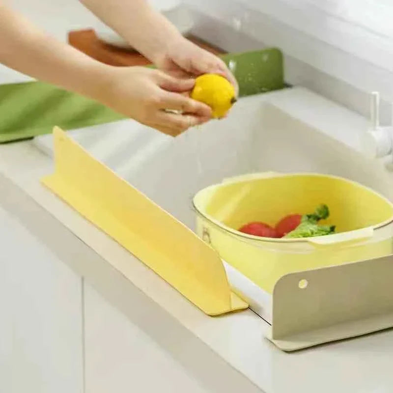 Flexible silicone sink splash guard with suction cups, placed along the edge of a kitchen sink to prevent water spills.