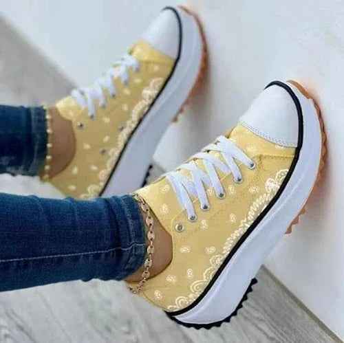 White and pastel canvas sneakers with a colorful 2022 pattern, displayed from a side angle on a plain background.