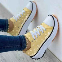 White and pastel canvas sneakers with a colorful 2022 pattern, displayed from a side angle on a plain background.