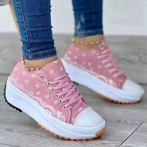 White canvas sneakers with a colorful patterned design and white soles, styled for casual wear.