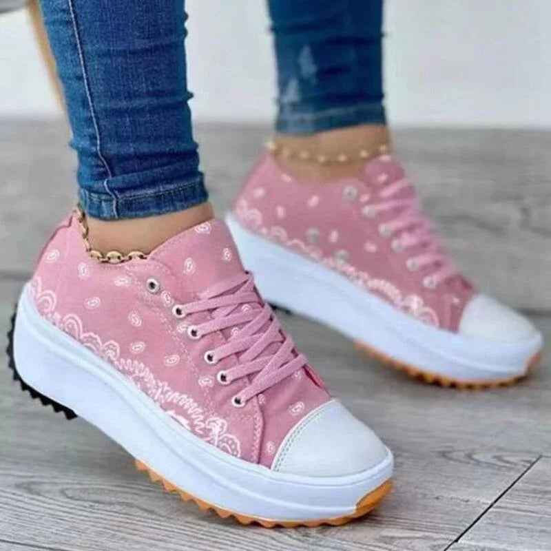 White canvas sneakers with a colorful pattern, lace-up design, and a thick rubber sole, shown on a plain background.