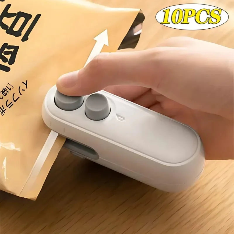 White portable mini heat sealer placed on a wooden surface with a snack bag sealed.