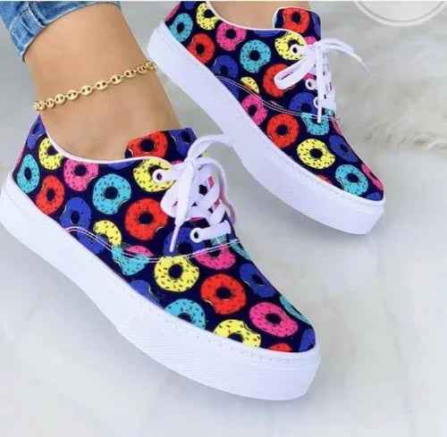 White women’s sneakers with colorful graffiti designs, thick sole, and lace-up front, displayed at a slight angle.