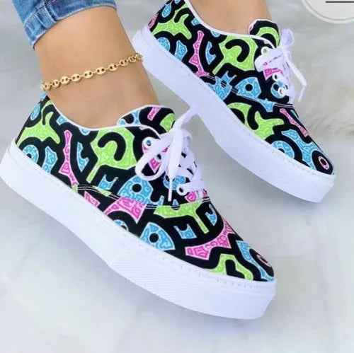 White women’s sneakers with colorful graffiti designs, lace-up closure, shown on a plain background.
