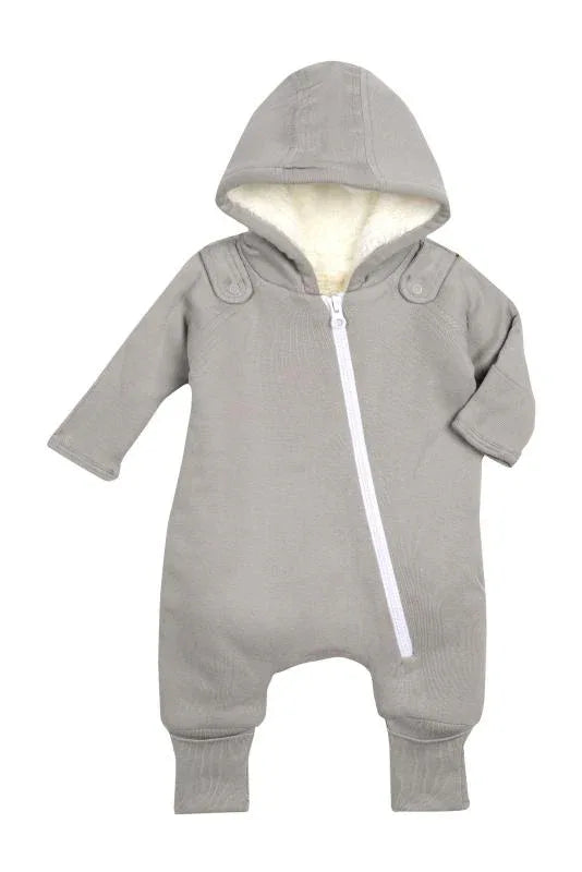 Close-up of baby in gray cozy jumpsuit with slanted zipper and bib, smiling indoors.
