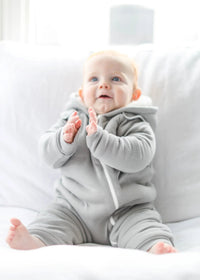 Detailed view of gray fleeced jumpsuit fabric and zipper next to matching bib on white background.