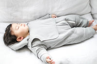 Flat lay of gray jumpsuit and attachable bib showing fleece lining and slanted zipper design.