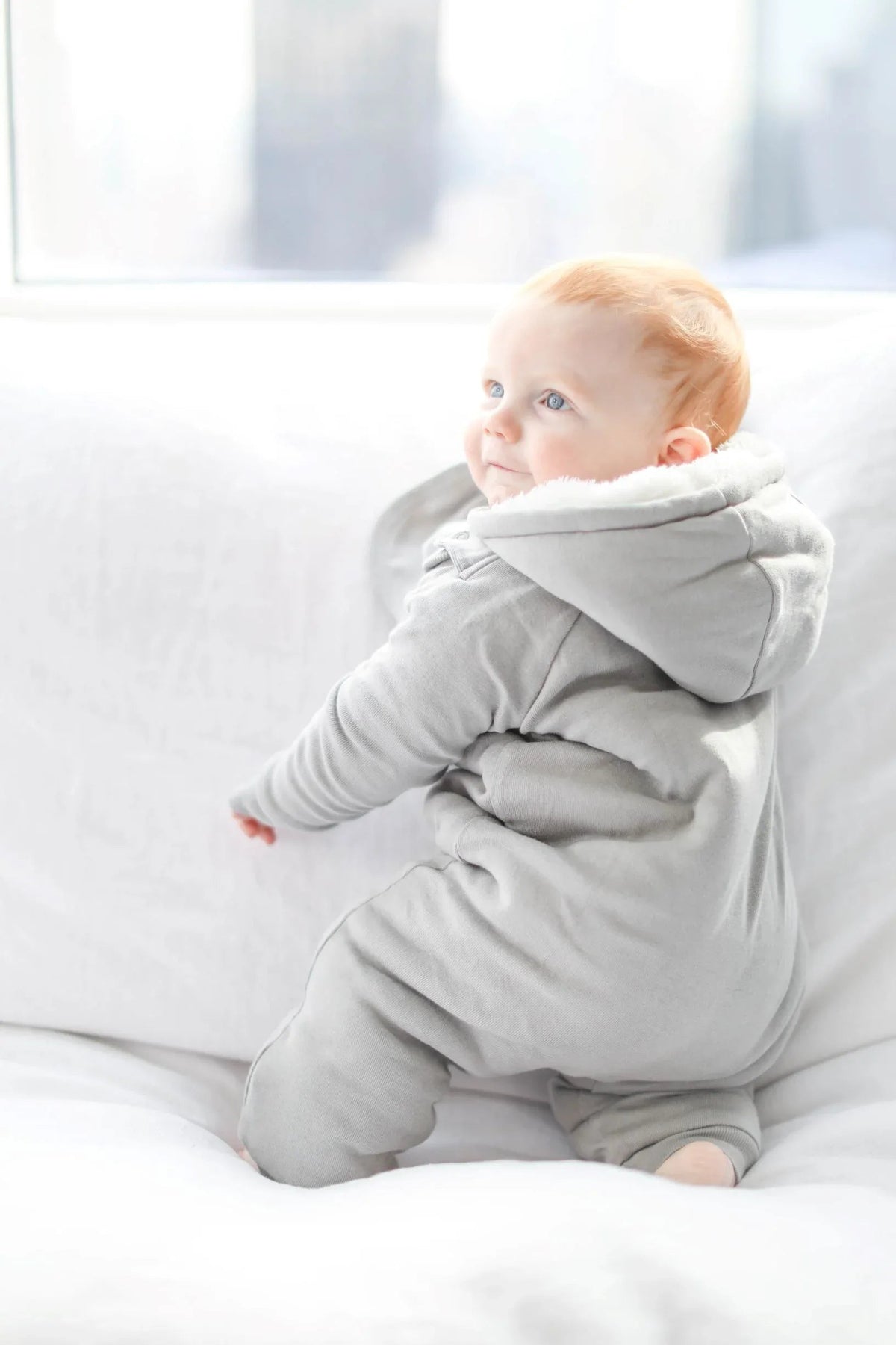 Baby's hand showing convertible covers on gray fleeced jumpsuit sleeve.