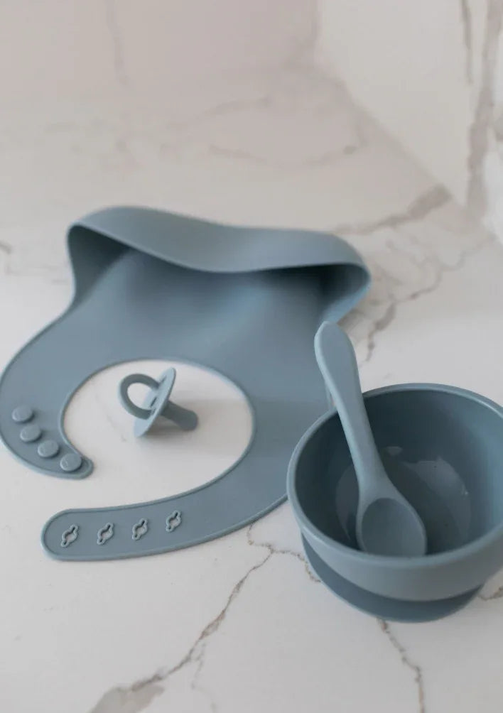 Blue silicone bib with adjustable neck strap, designed for kids, laid flat on white background.