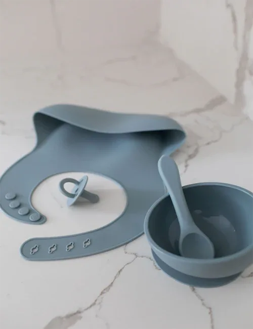 Close-up of blue silicone bib showing textured catching pocket for crumbs and spills.