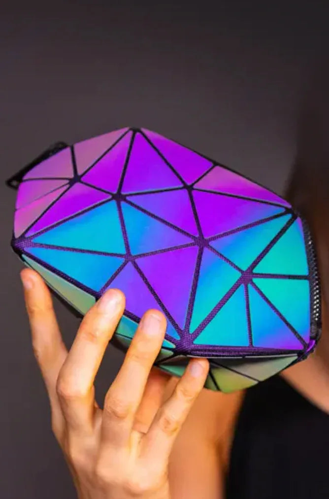 The Lumination Makeup Bag compared with a hand, displaying its portable dimensions and holographic effect.