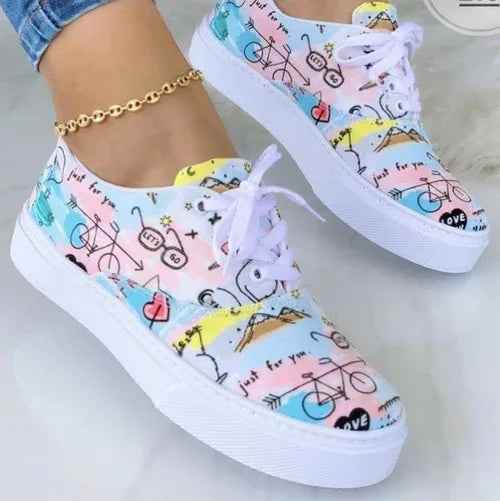 White women's sneakers with colorful graffiti design details and chunky soles on a plain background.
