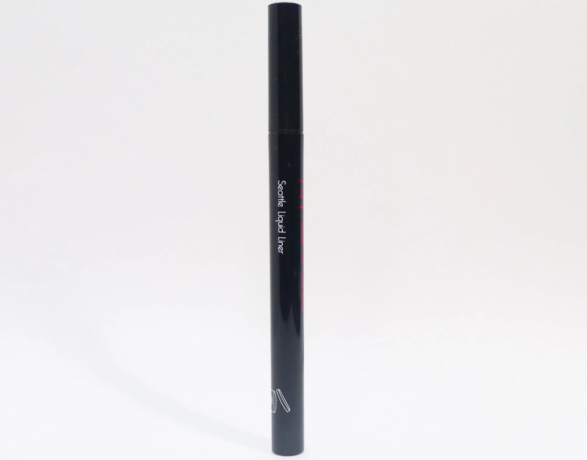 Queen Anne Liquid Liner pen closed, resting on a wooden surface with a blurred background.