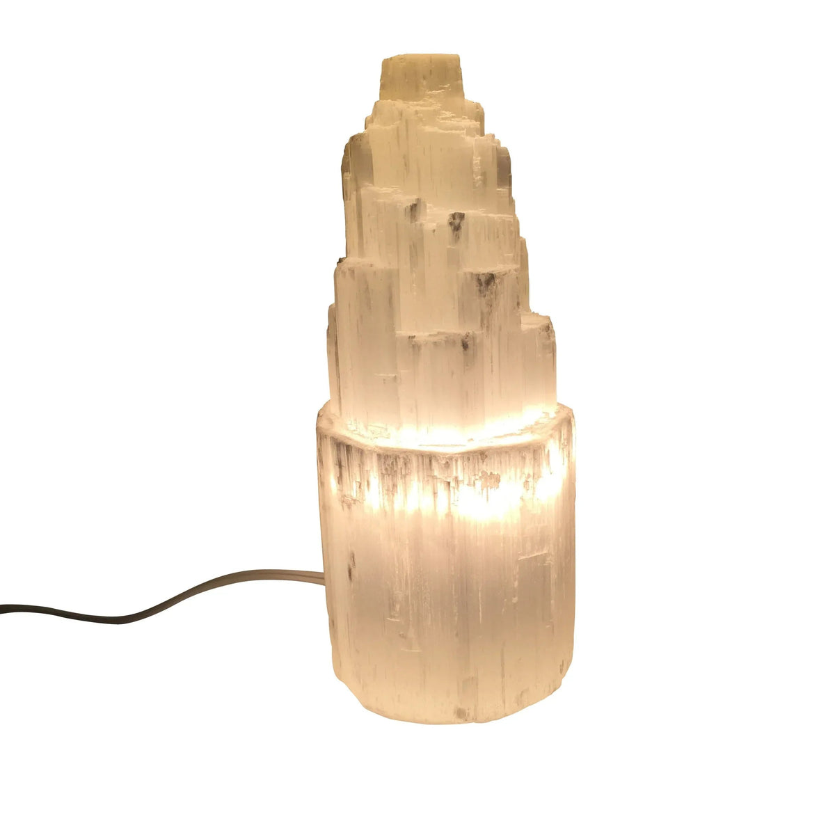 Small selenite skyscraper lamp glowing warmly on a wooden surface