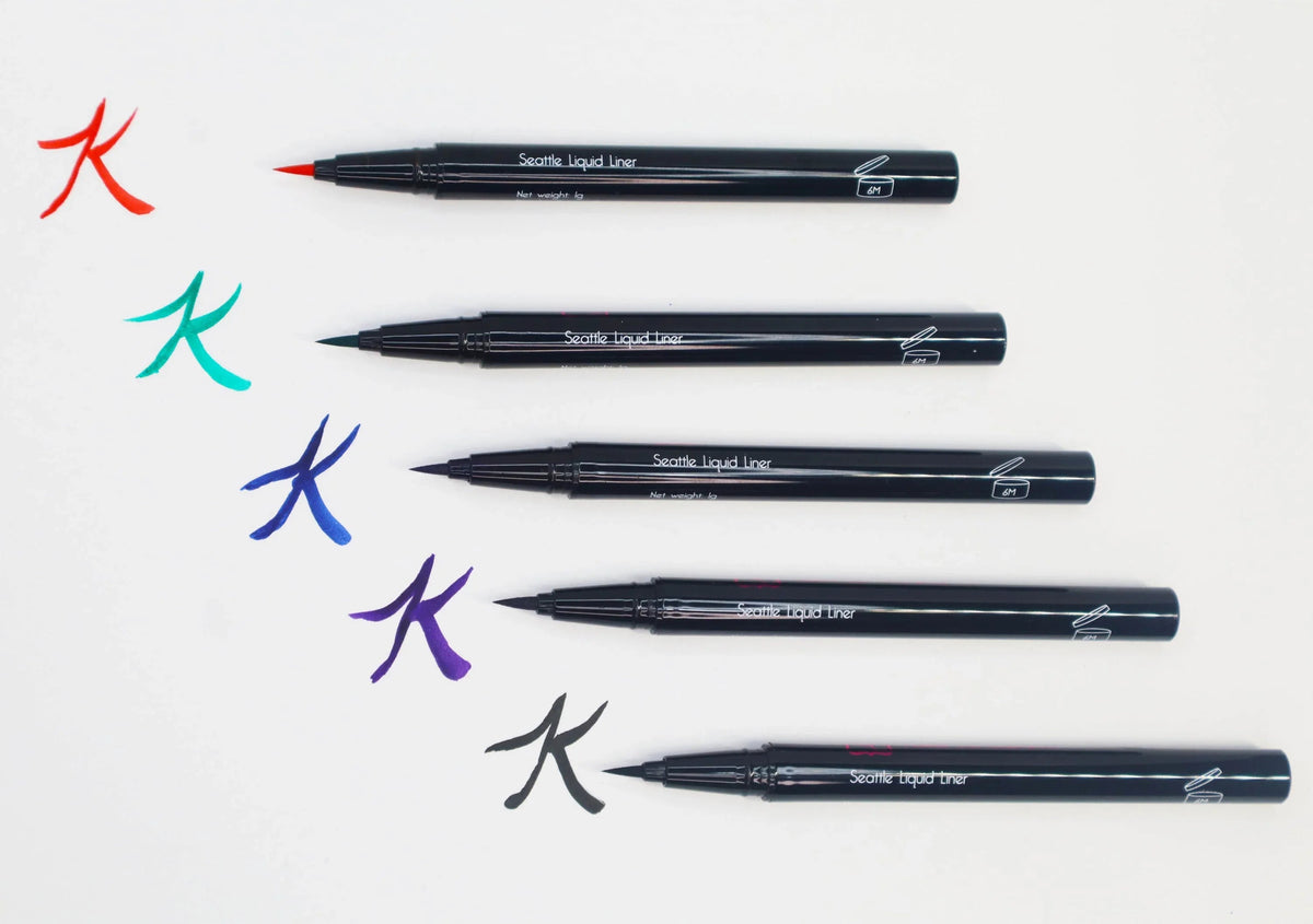 Swatches of Queen Anne Liquid Liner showing vibrant royal blue lines on light skin.