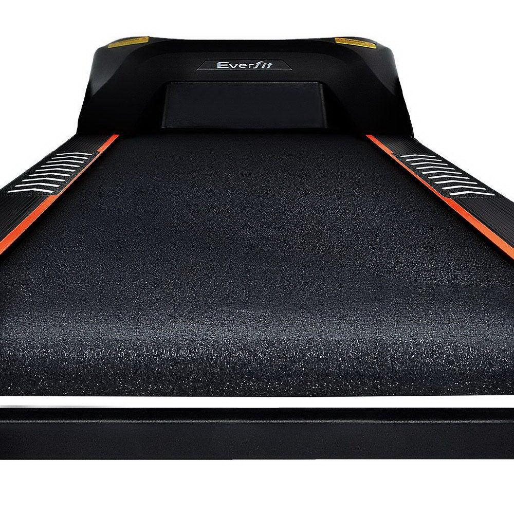 Treadmill folded upright for compact storage in a home gym setting.