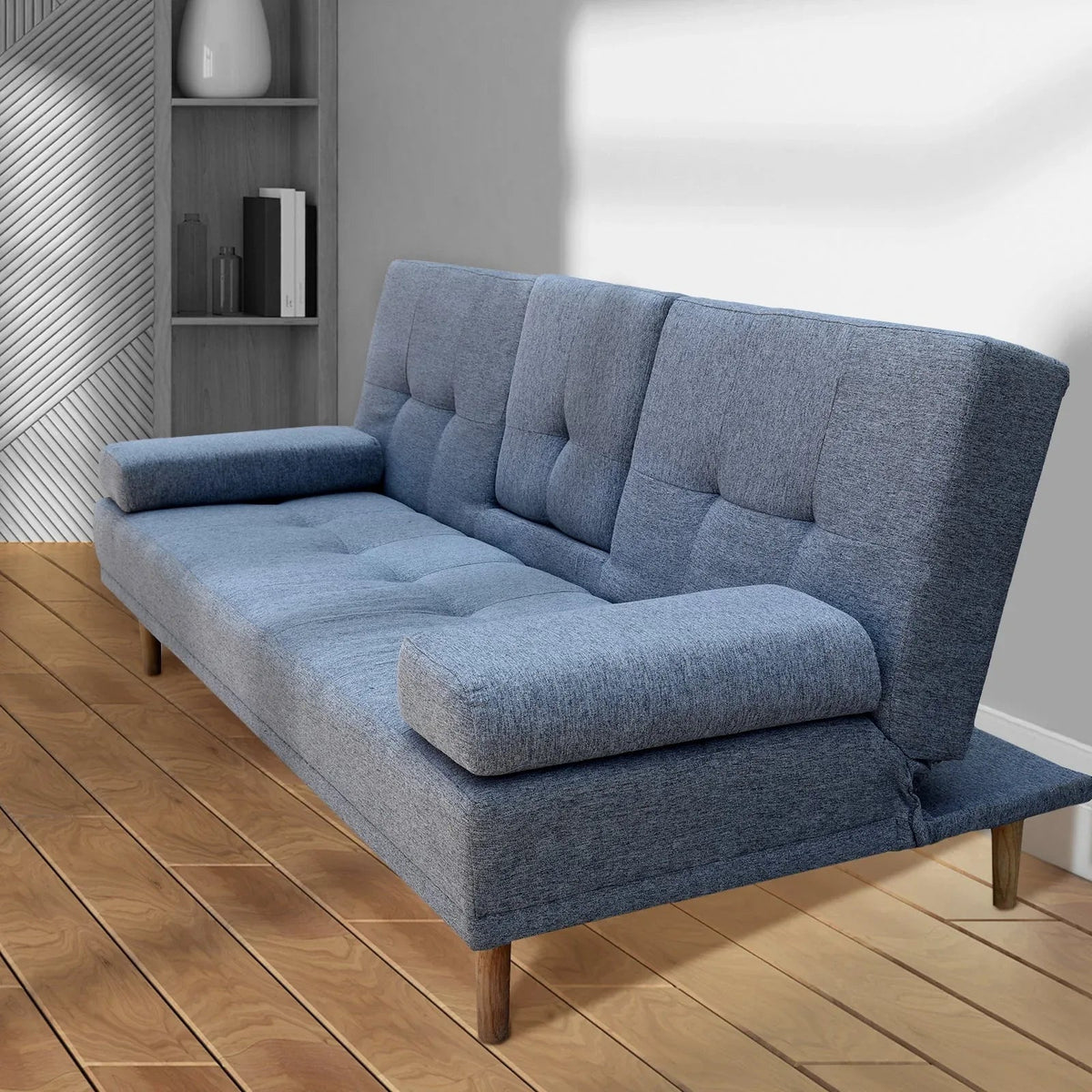 Grey sofa bed with cupholder pull-down feature and wooden legs on hardwood floor.