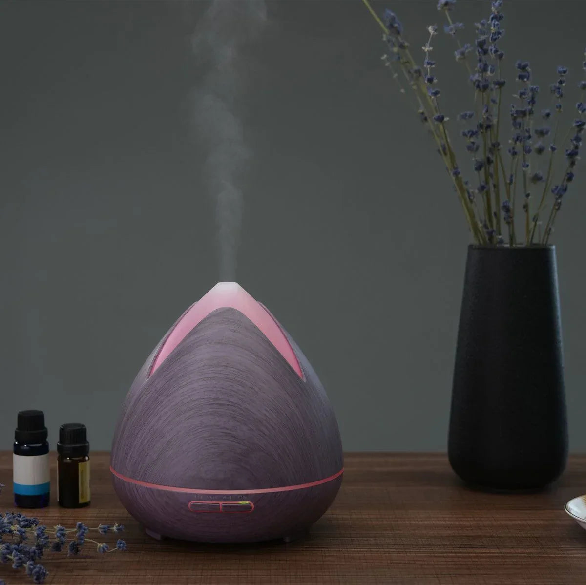 Ultrasonic diffuser on desk with soft light and green plant background.