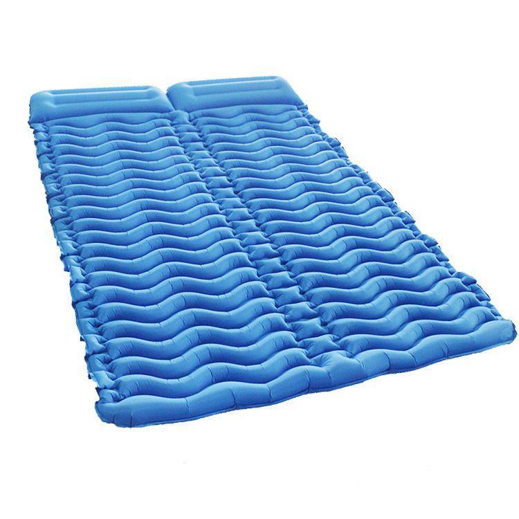 Inflated double two-person camping sleeping pad with V-shaped air chambers lying on grass outdoors.