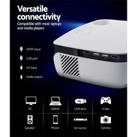 Devanti projector placed on a table projecting a colorful image on a wall in a dark room.