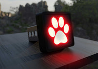 Close-up of a black Paw Print LED Hitch Cover with brake light glowing red