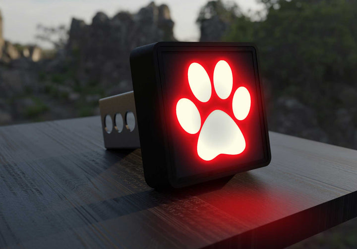 Close-up of a black Paw Print LED Hitch Cover with brake light glowing red