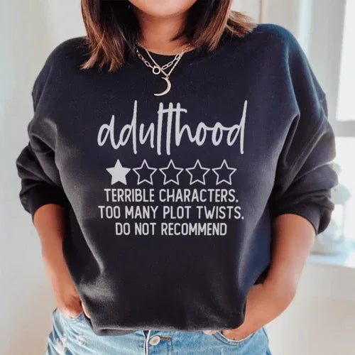 Black sweatshirt showing front design with bold text about adulthood and plot twists
