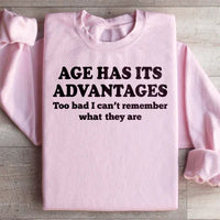 Close-up of peach-colored sweatshirt featuring "Age Has Its Advantages" text design.