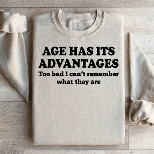Peach sweatshirt displayed flat with prominent white "Age Has Its Advantages" lettering.