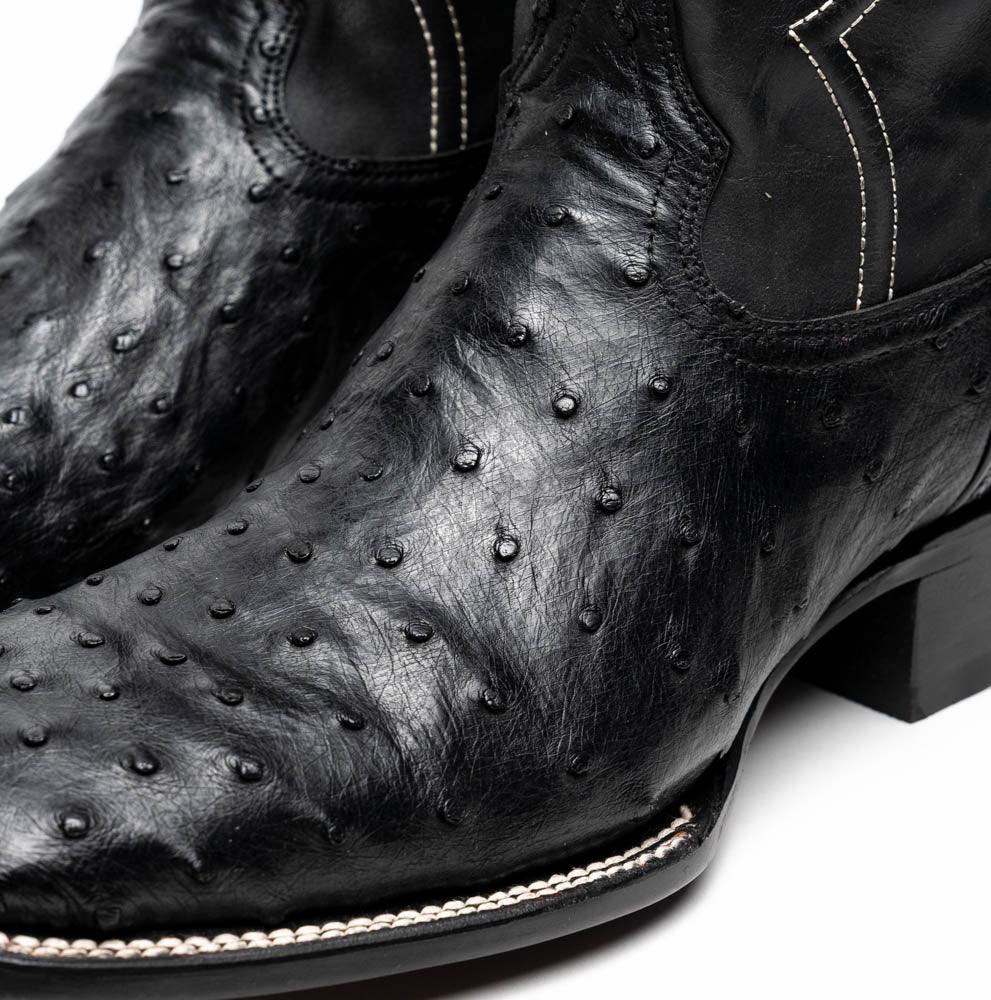 Top angled view of black ostrich skin cowboy boot displaying square toe and leather texture.