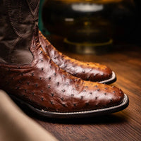 Side view of man walking in brown ostrich leather cowboy boots with square toe